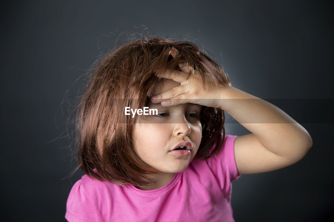 Close-up of girl with head in hand against black background