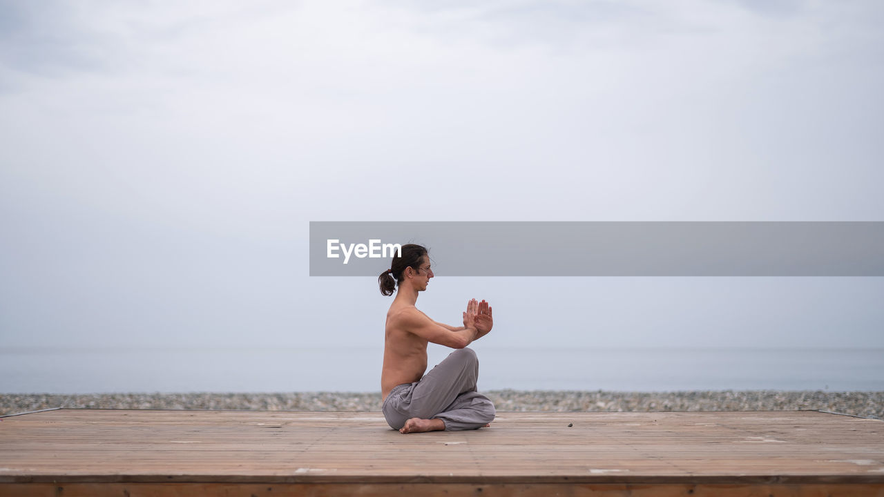 side view of woman sitting on beach