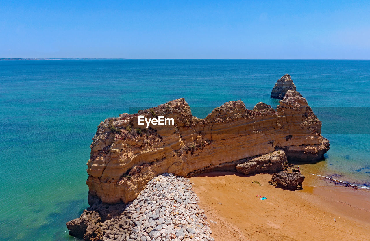 Rock formation on beach against blue sky