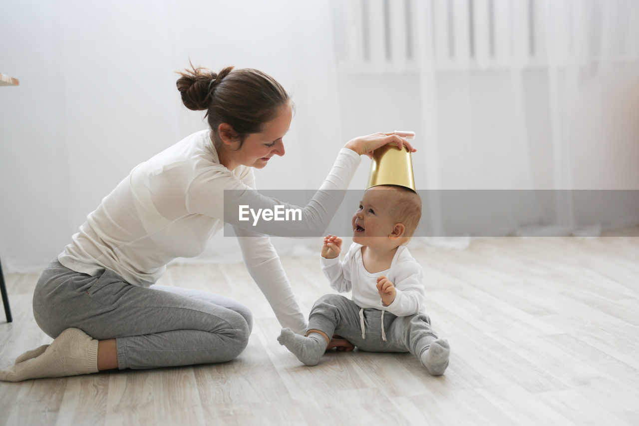 Funny baby 10 months with his mother playing with a pot in the kitchen, lifestyle 