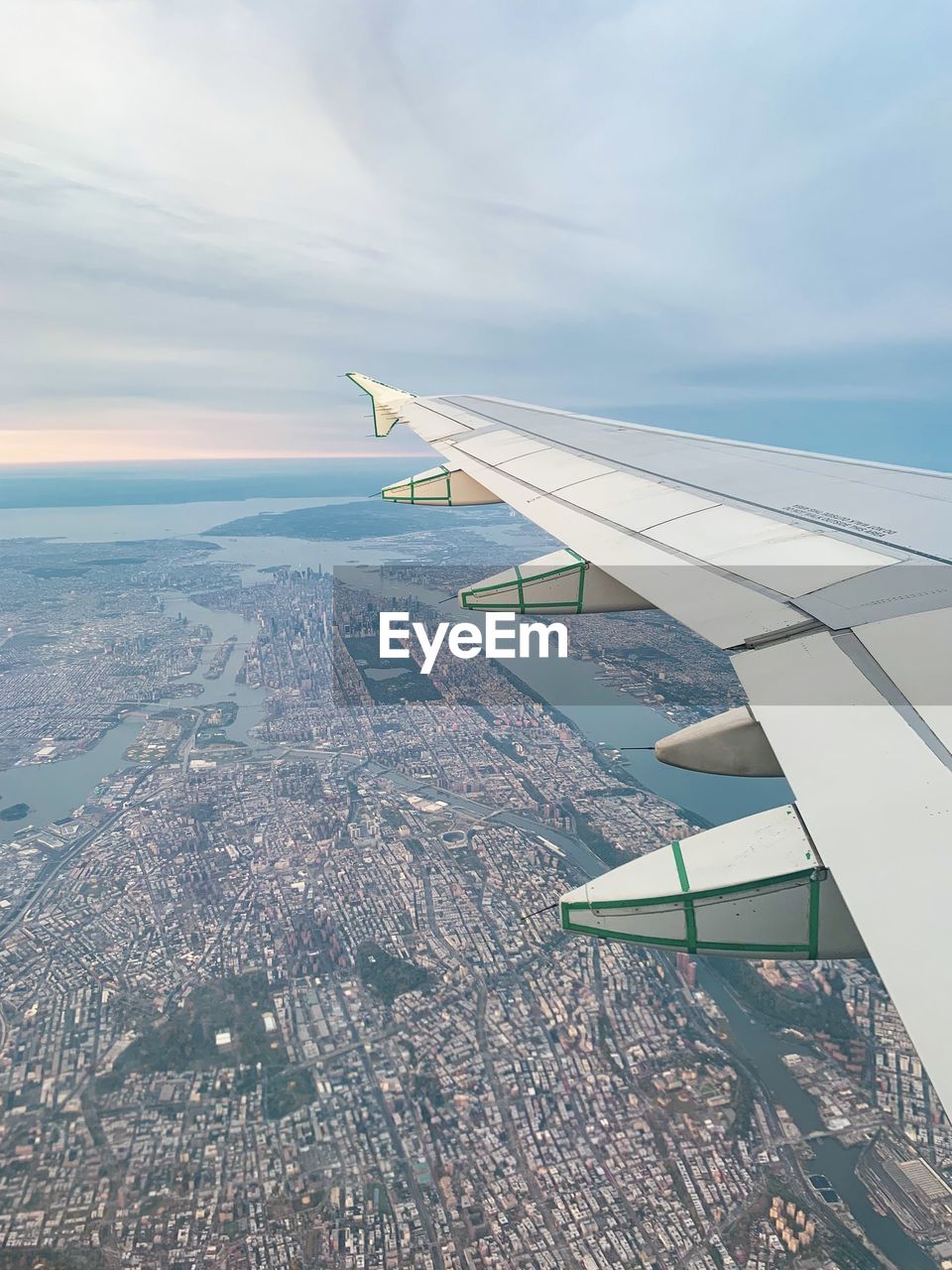 Aerial view of airplane flying over manhattan cityscape against sky