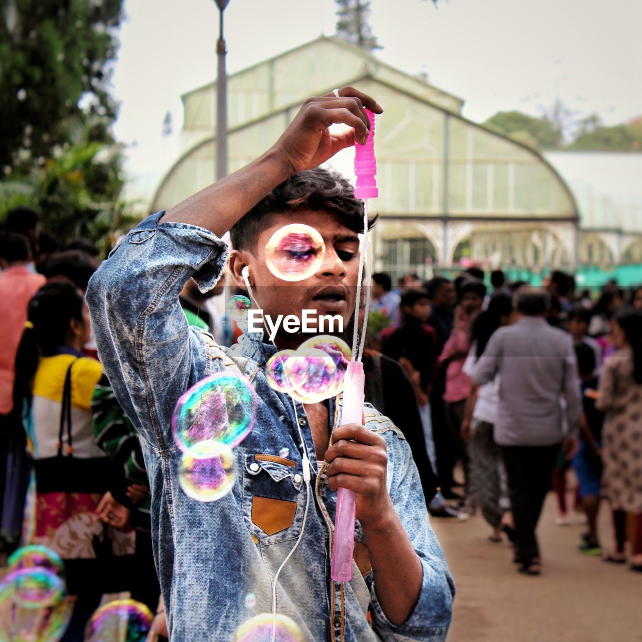 Portrait of young man blowing bubbles in city