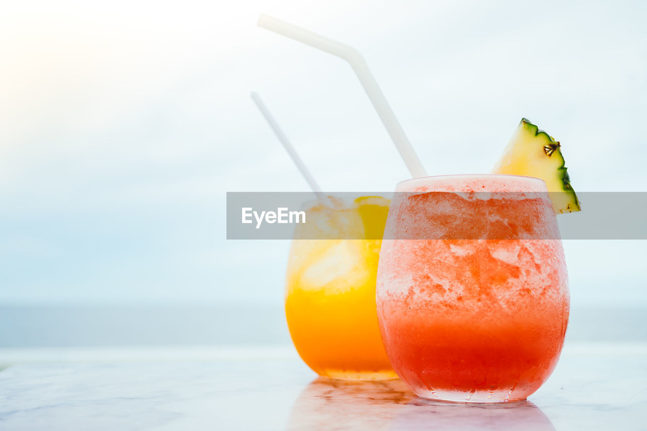 Close-up of drinks on table against sea