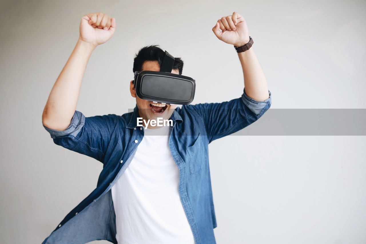 MIDSECTION OF MAN USING PHONE WHILE STANDING ON LAPTOP