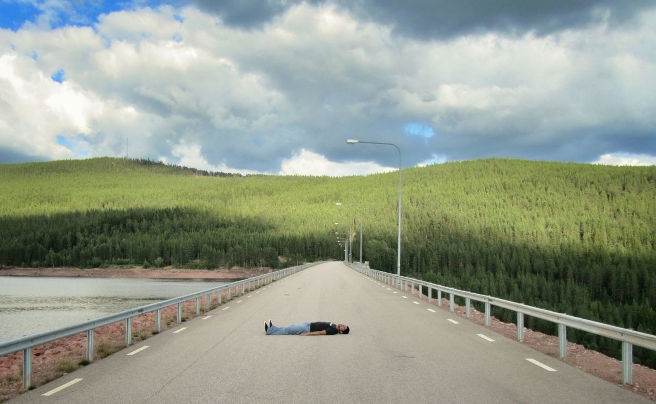 EMPTY COUNTRY ROAD AGAINST CLOUDY SKY