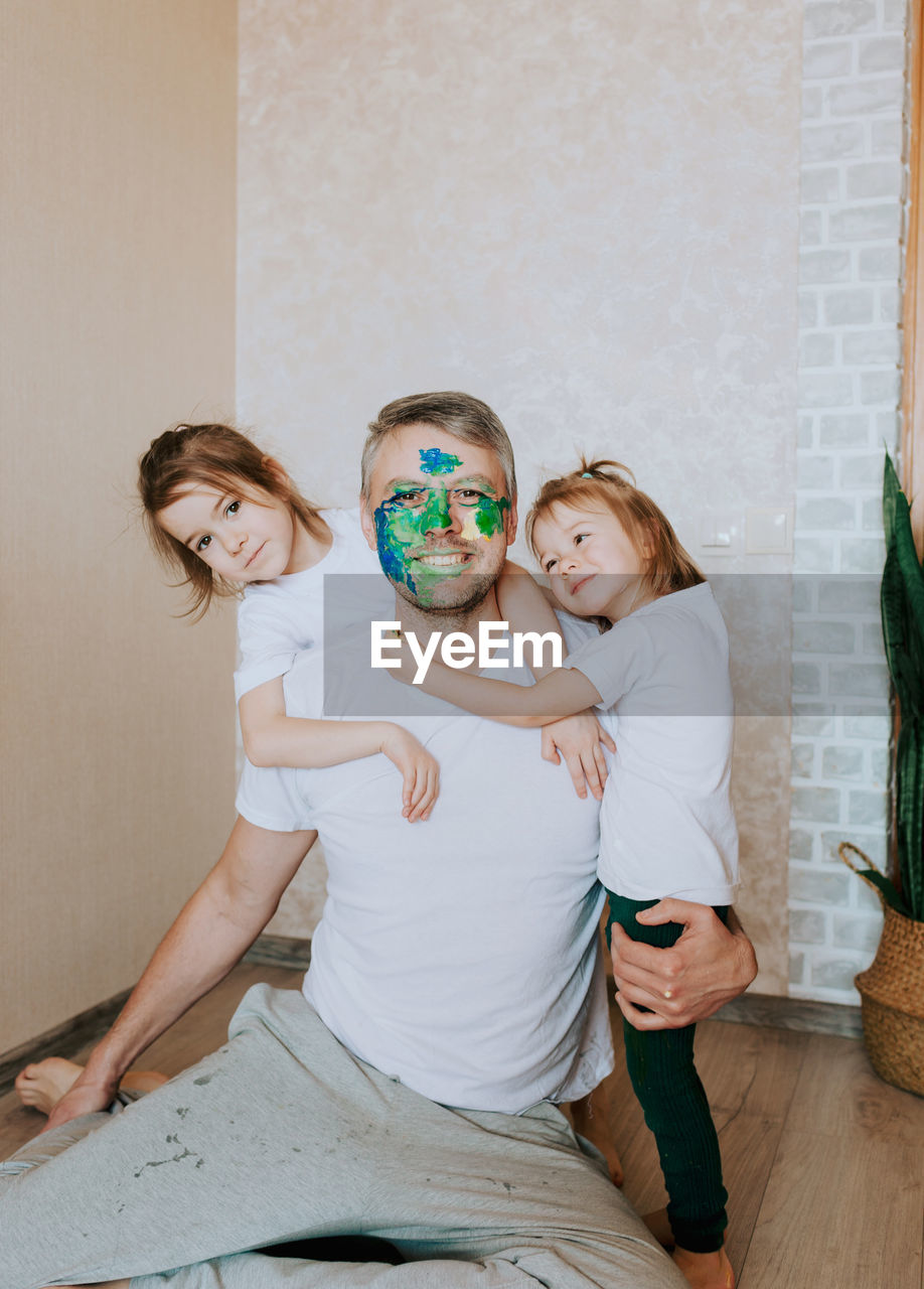 Father with painted face playing with daughter at home