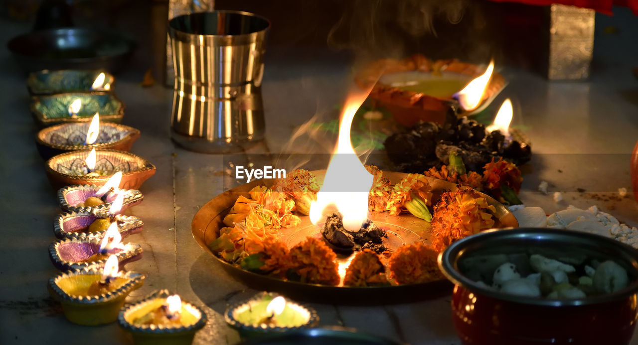 Close-up of illuminated aarti thali on floor during traditional festival