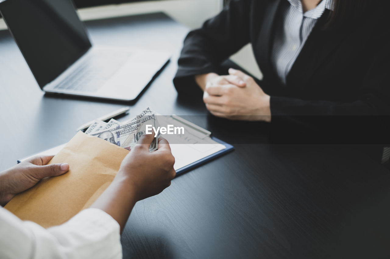 Close-up of client bribing lawyer at desk in office