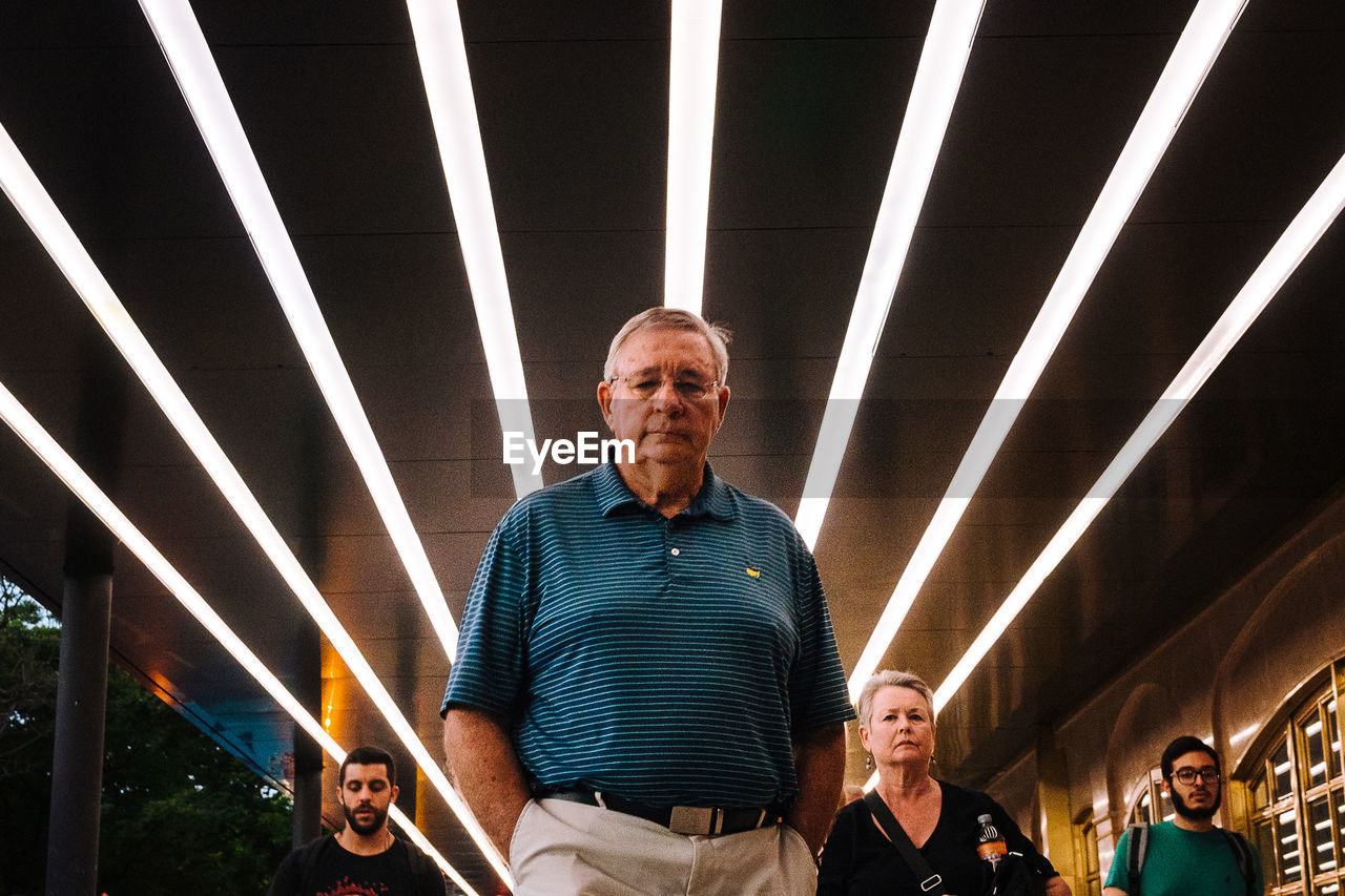 PORTRAIT OF MAN STANDING ON ILLUMINATED BUS