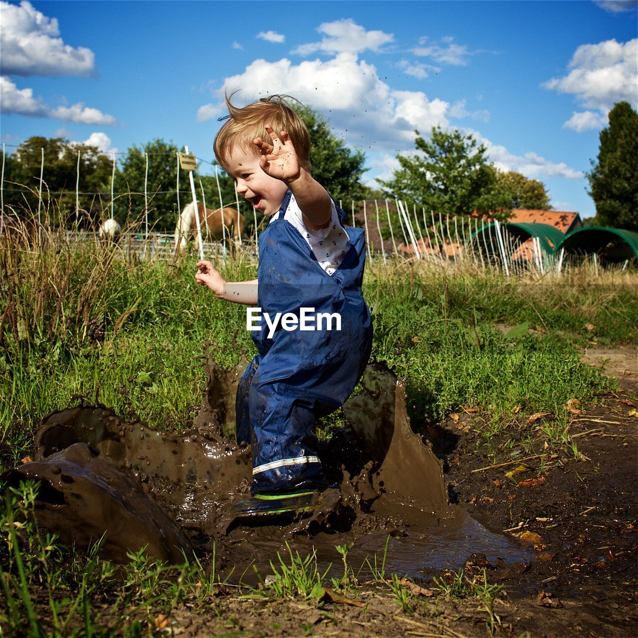 Full length of happy playful boy on muddy field