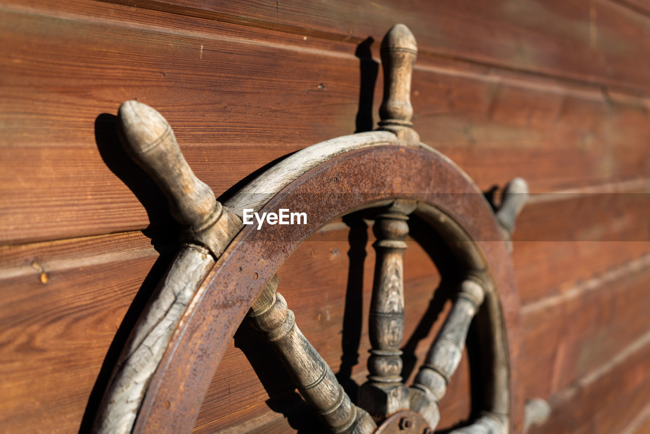CLOSE-UP OF OLD RUSTY WHEEL ON WOOD
