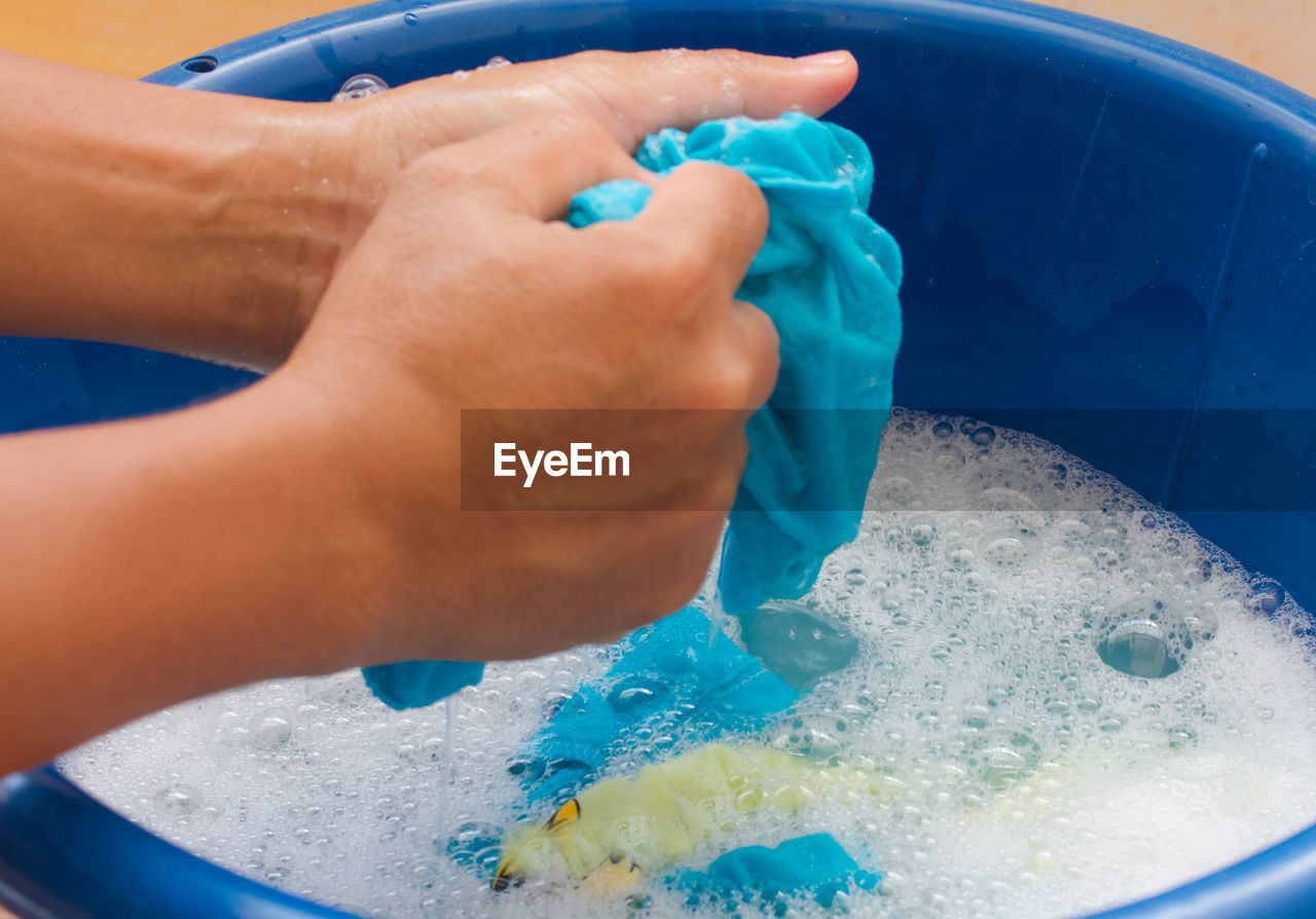 CLOSE-UP OF WOMAN HAND HOLDING WATER IN CONTAINER