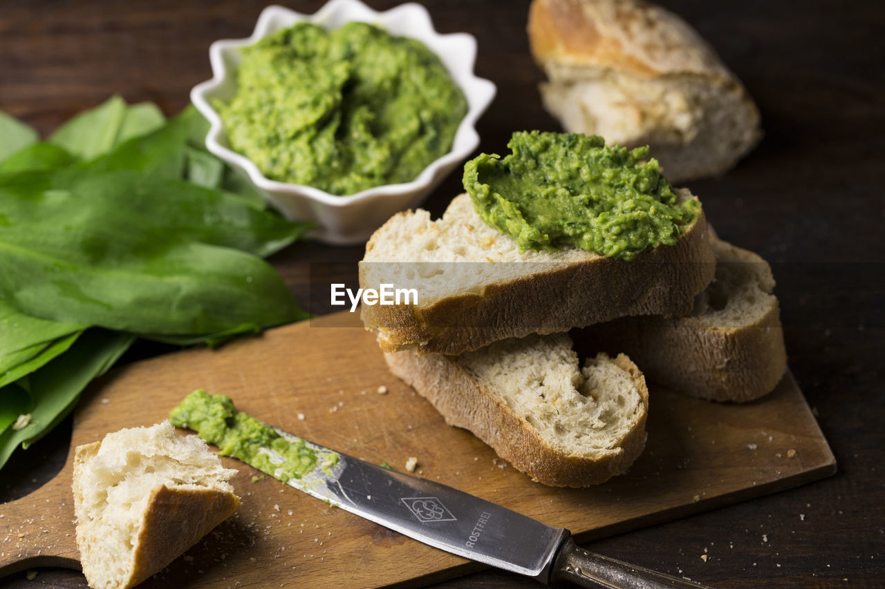 Close-up of bread with green paste and leaves on wooden table