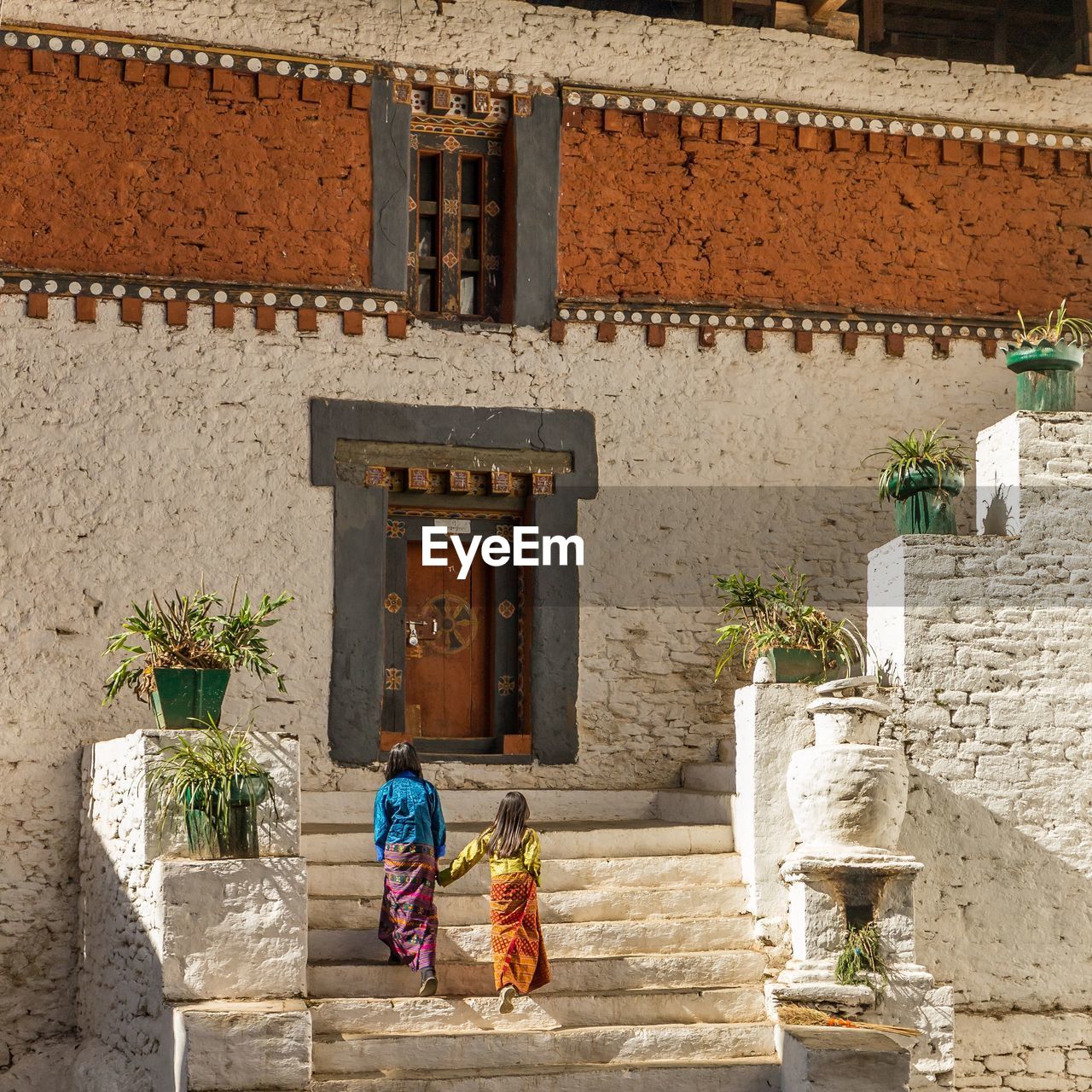 Sisters walking on steps against house