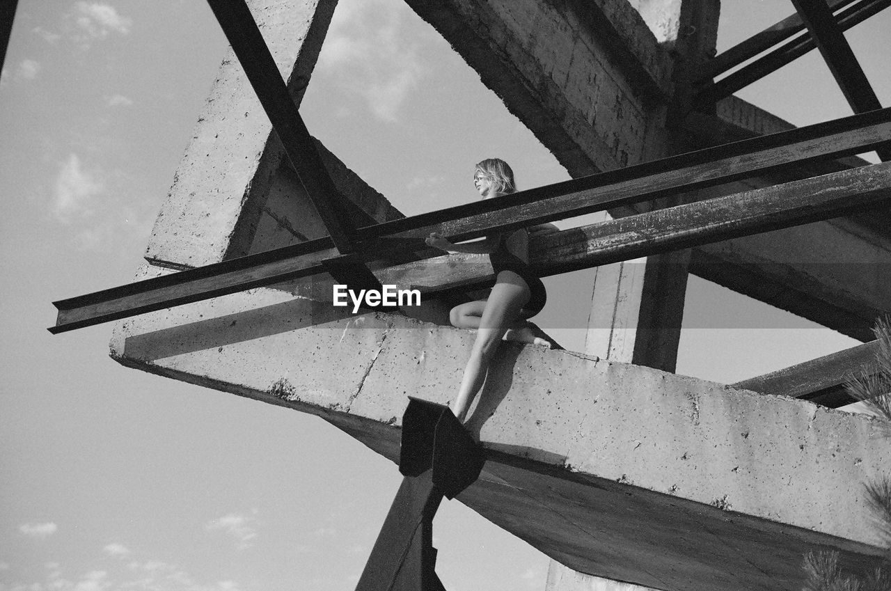 Low angle view of woman standing on built structure against sky