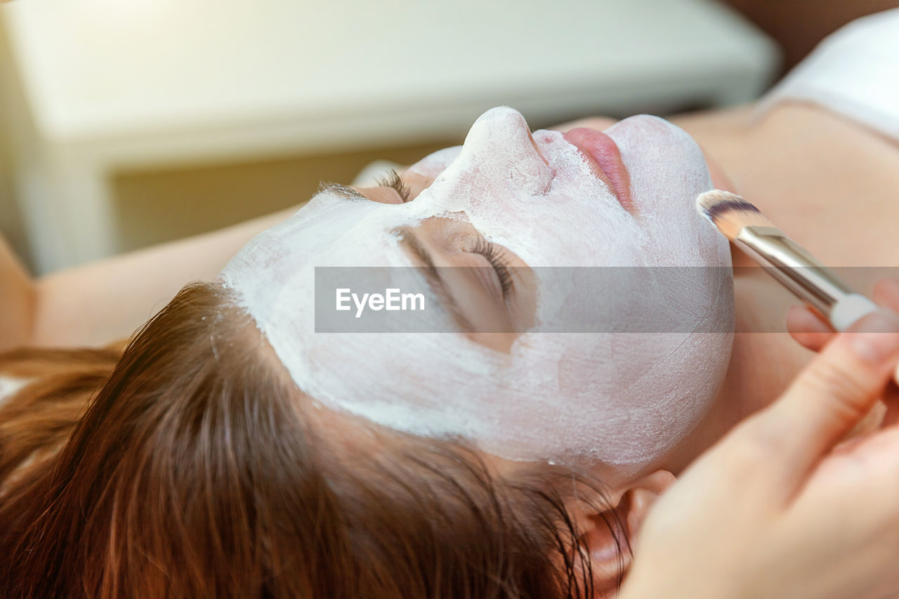 Cropped hand of beautician applying mask on clients face