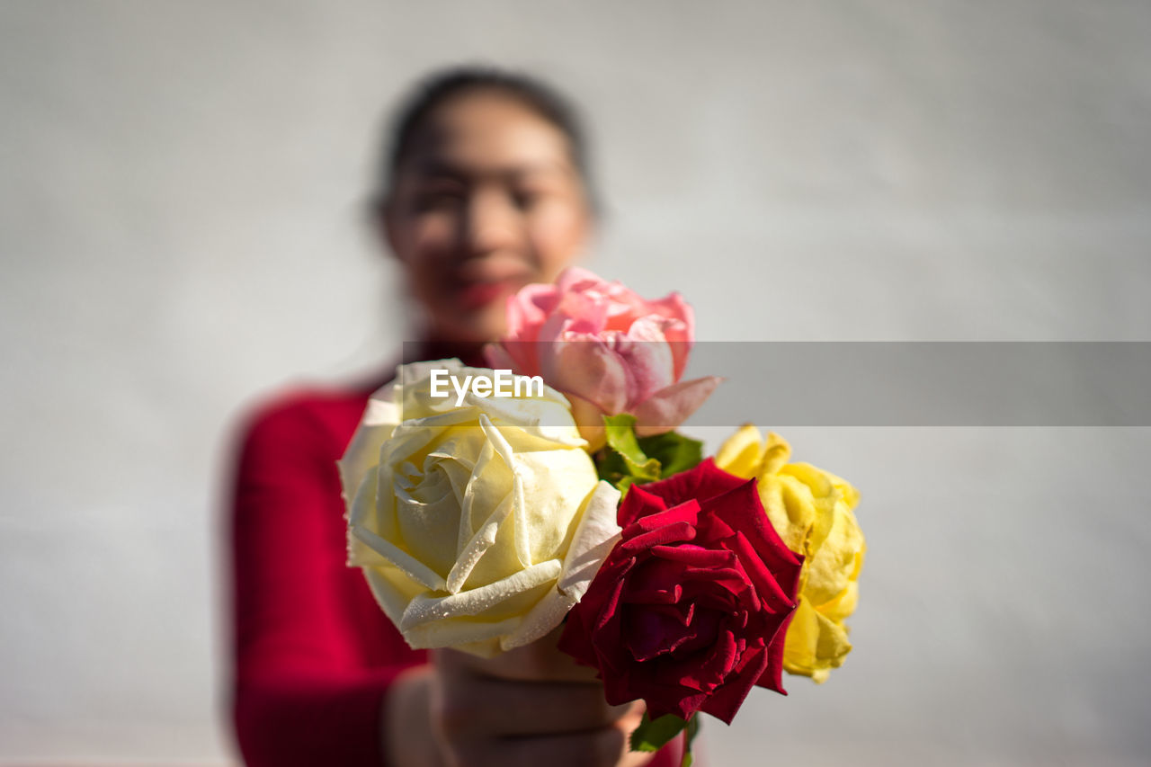 Asian lady showing rose bouquet at camera