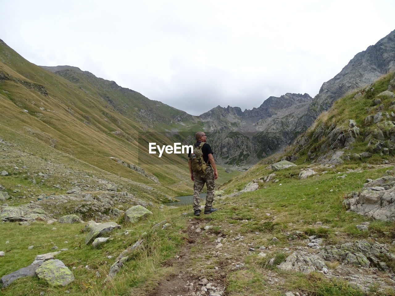 Rear view of man with backpack walking on land against sky