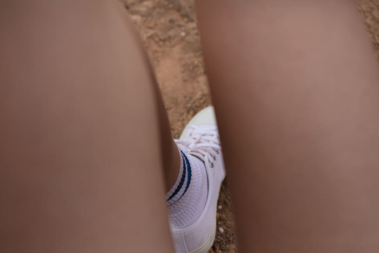 Low section of woman wearing white shoe