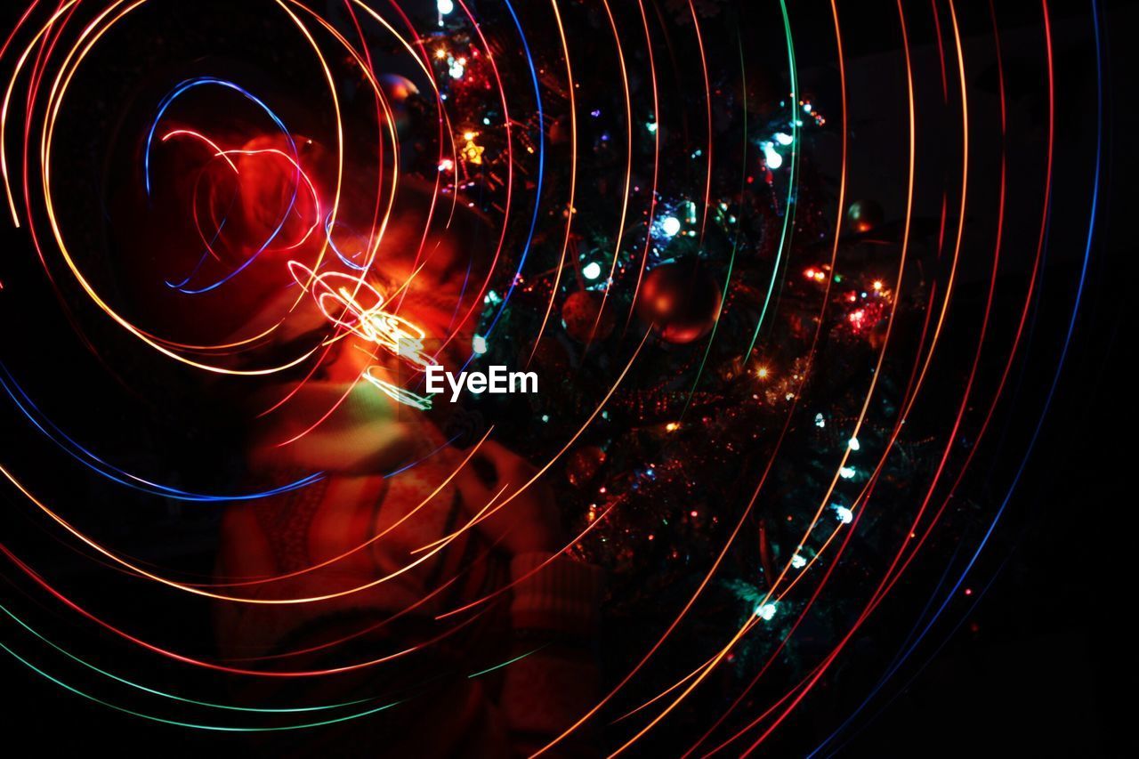 Digital composite image of person surrounded with spiral light trails at night