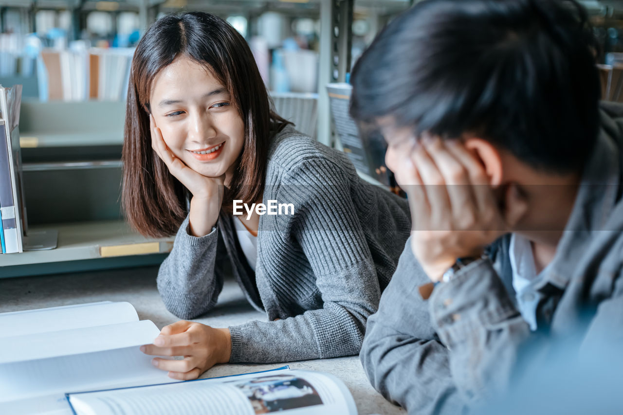 Portrait of smiling young woman using phone while sitting on table