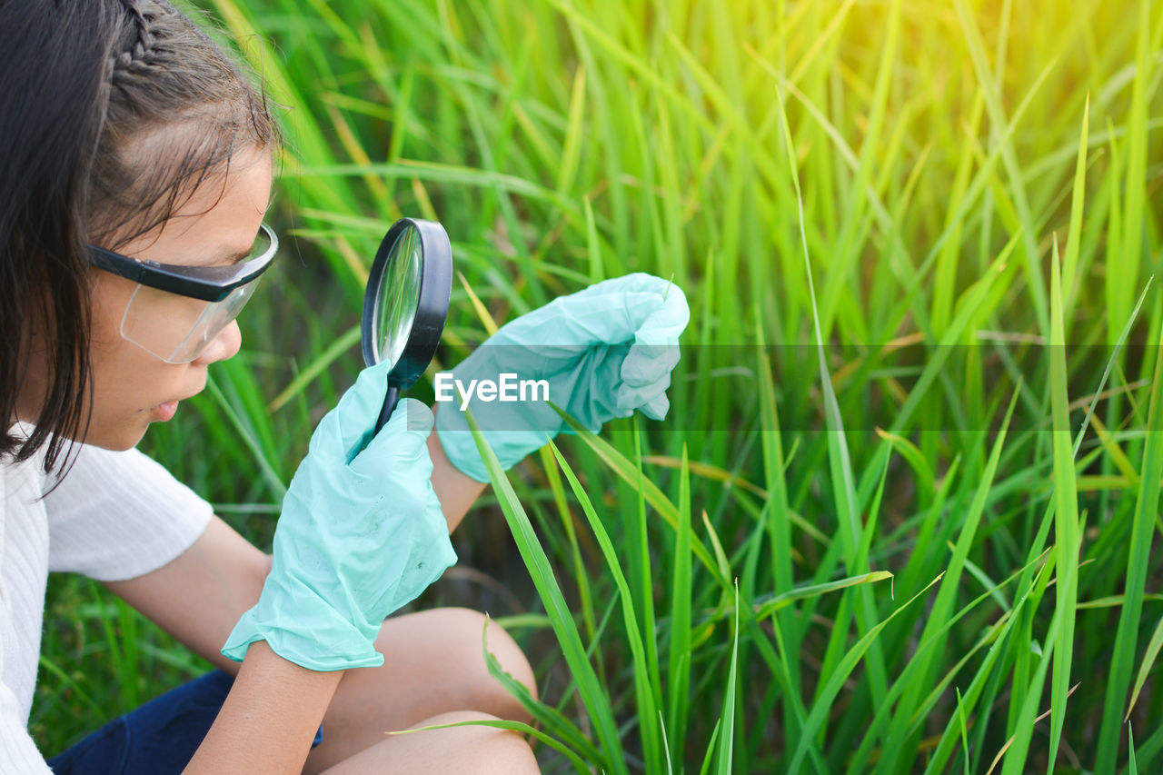 Girl examining plants through magnifying glass