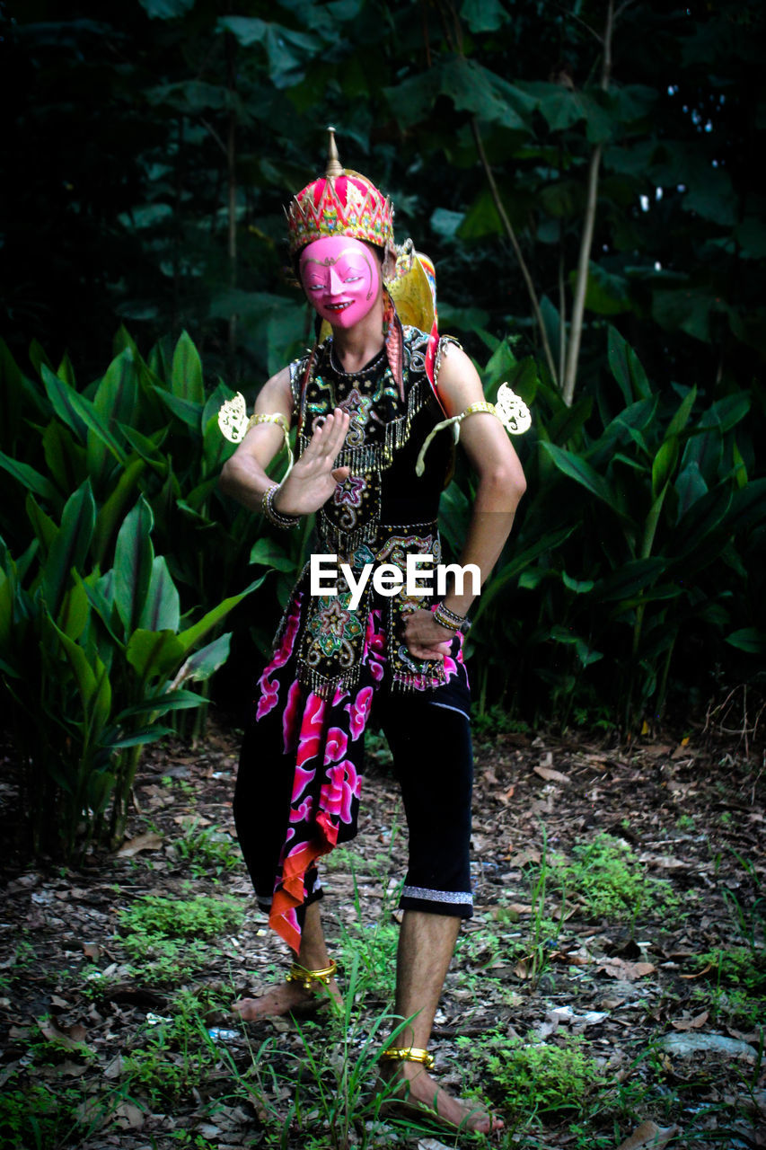 Full length of woman standing on field in forest