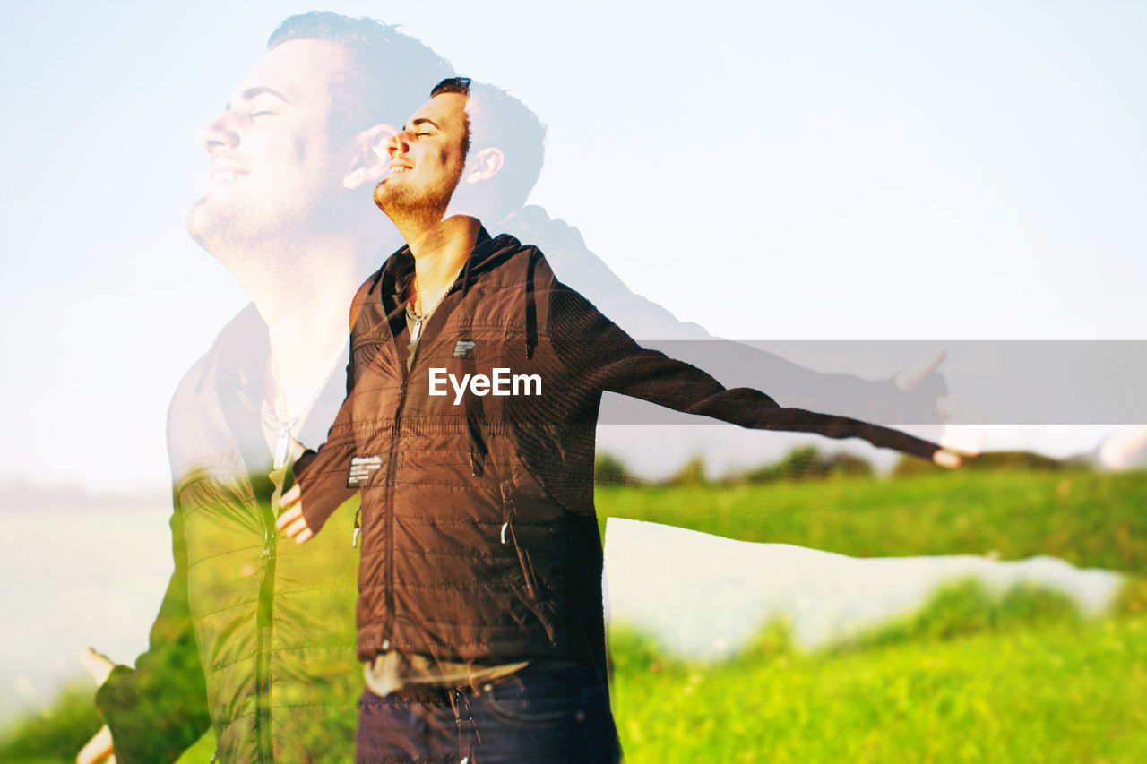 Double exposure image of man with arms outstretched