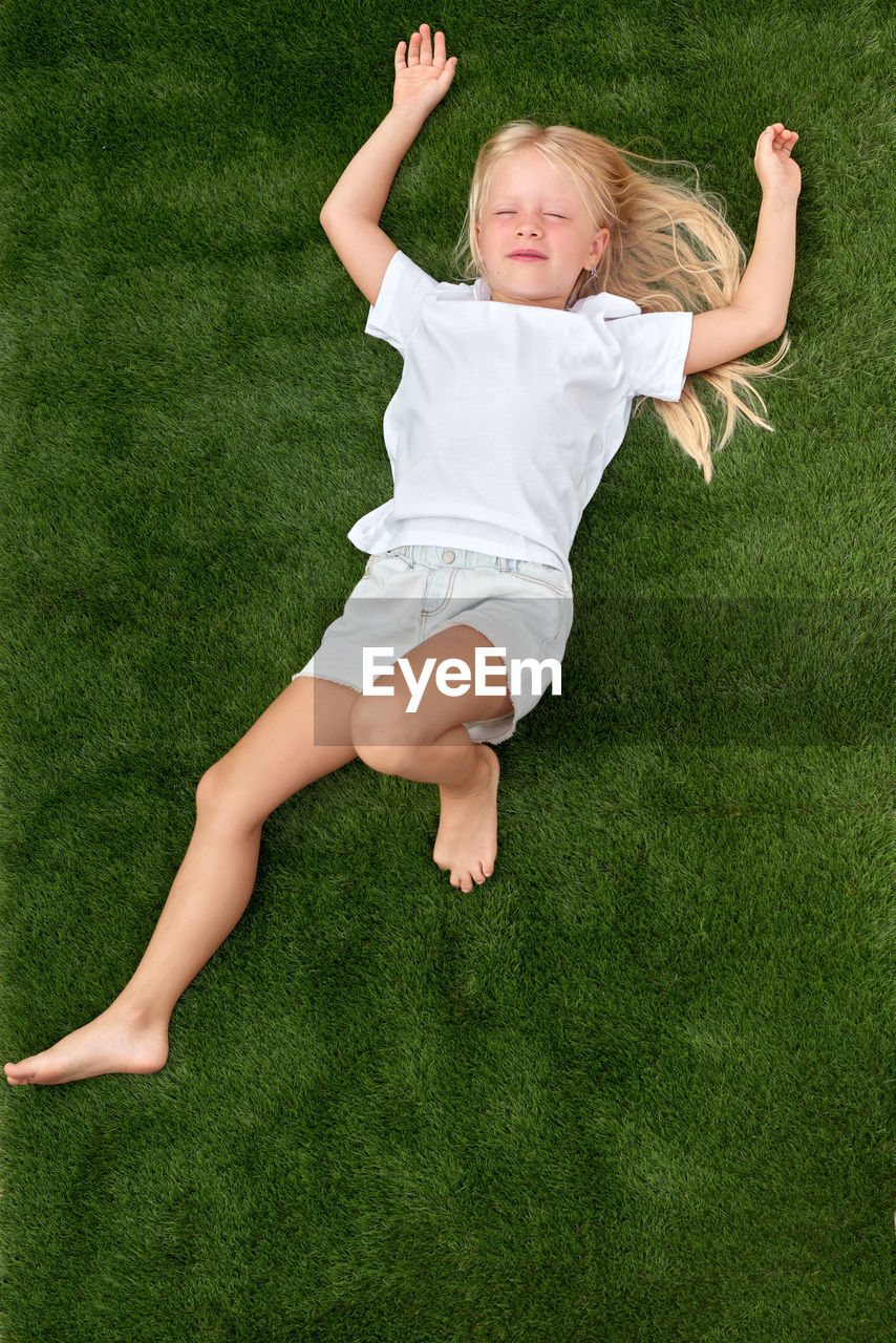 full length of boy playing with ball on grassy field