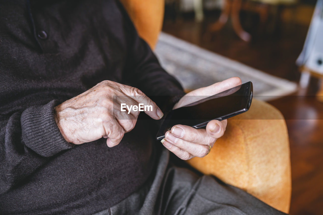 Hands of senior man using smartphone, close-up