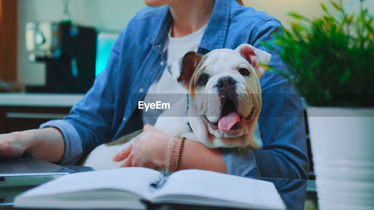 Midsection of woman with dog sitting on book