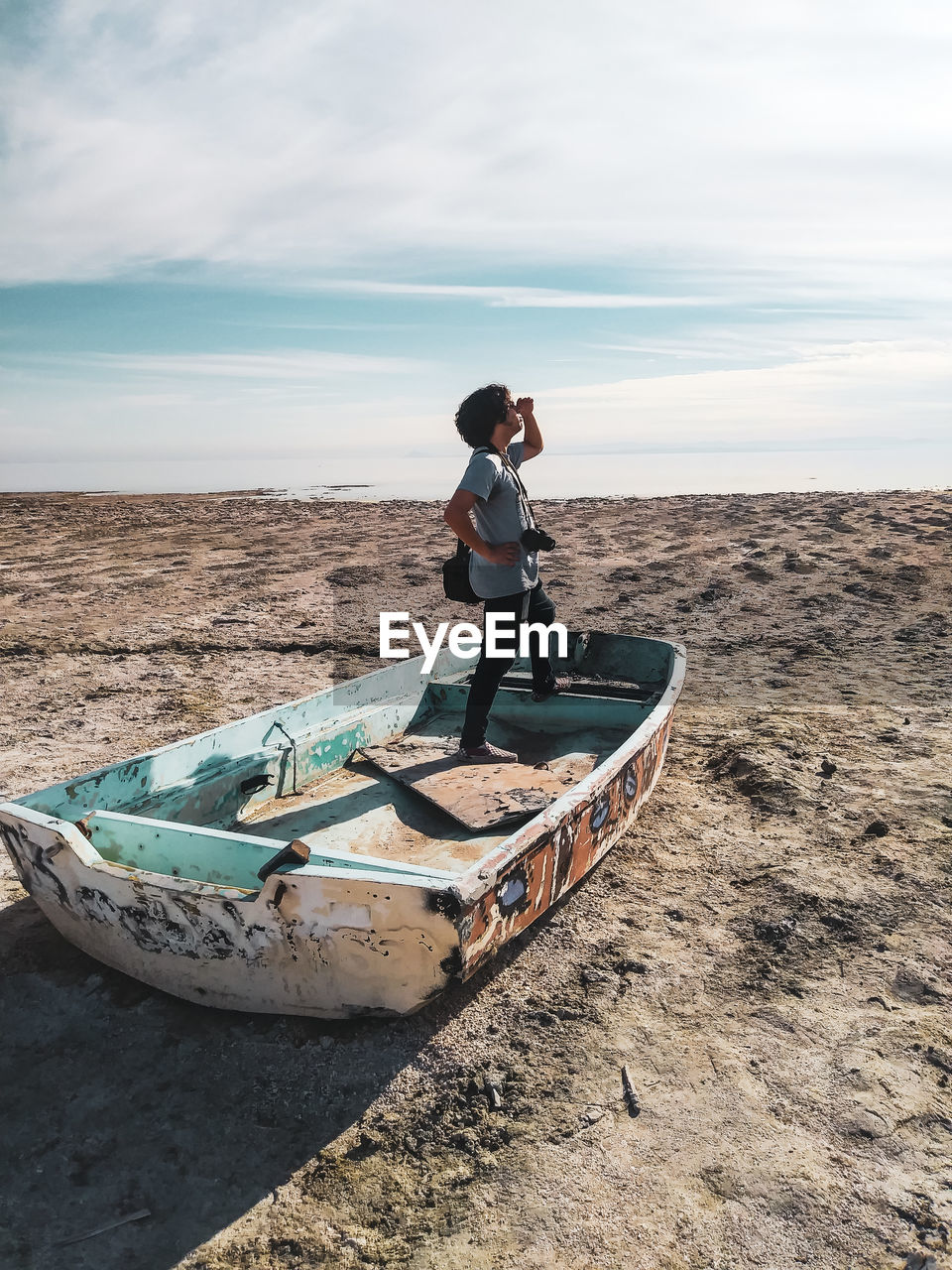 Man standing in boat at beach against sky