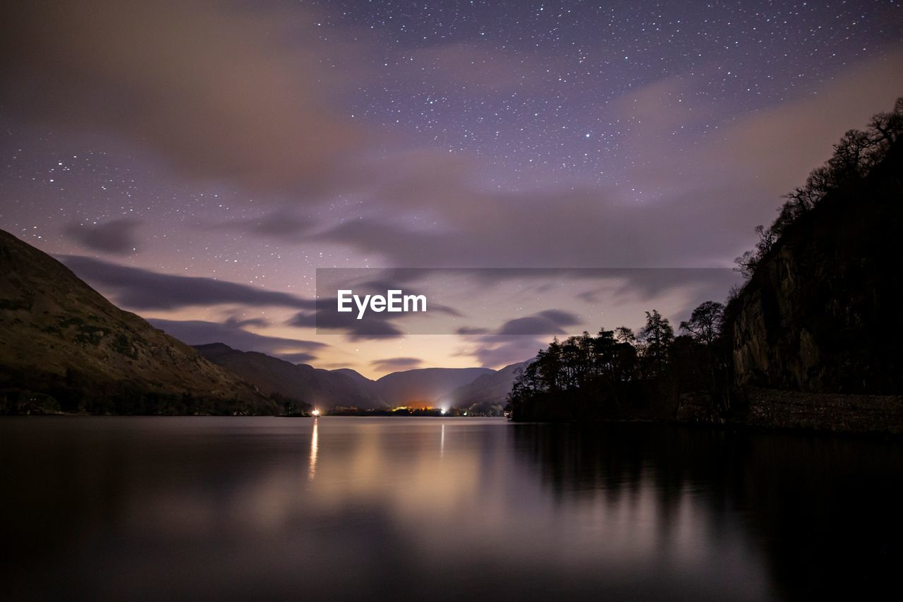 SCENIC VIEW OF LAKE BY MOUNTAINS AGAINST SKY AT NIGHT