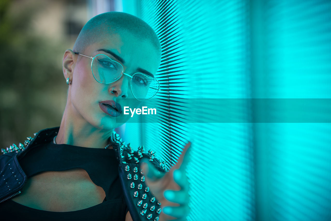 Portrait of young woman with shaved head standing against abstract backgrounds