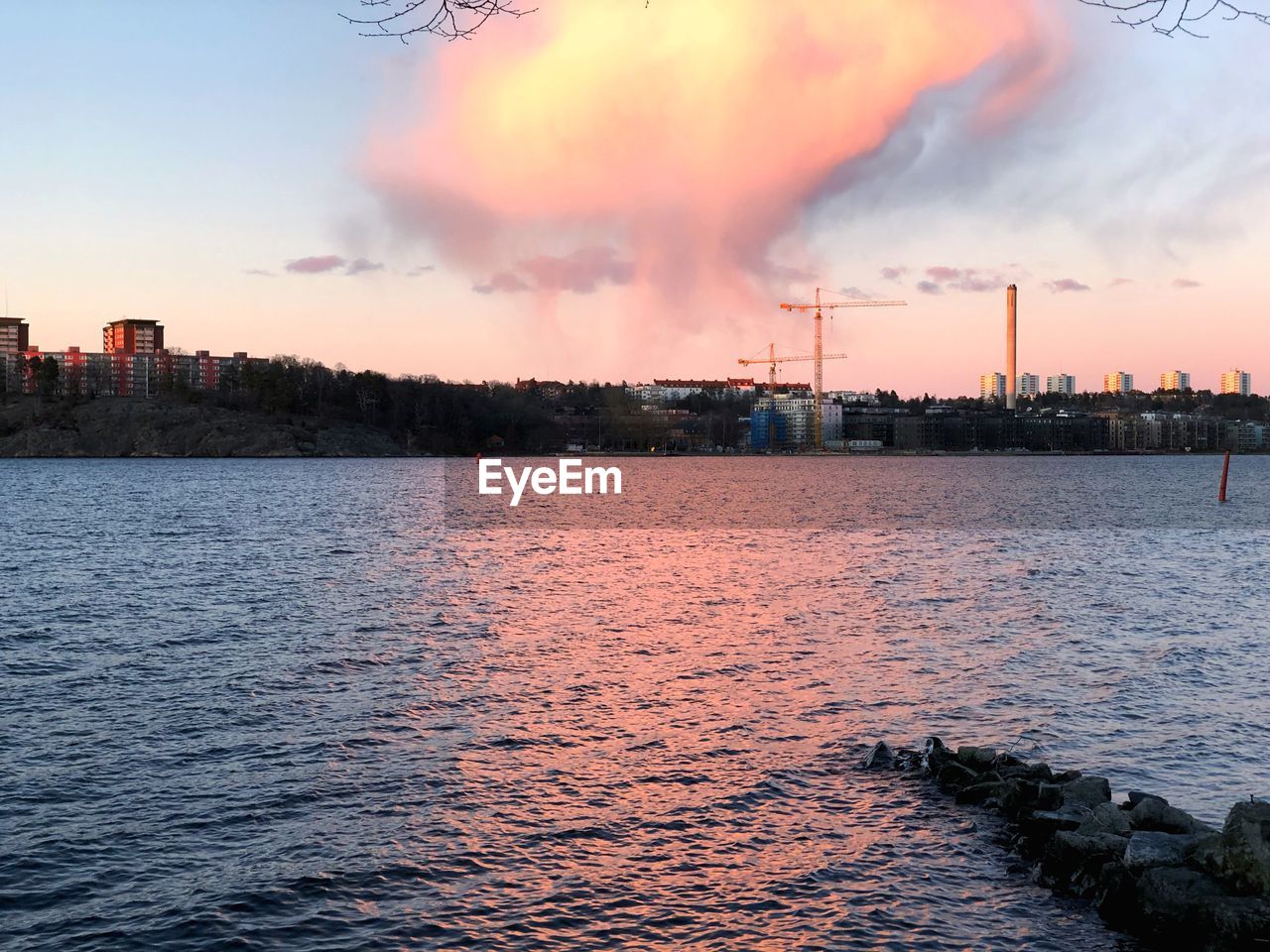 CITY BY RIVER AGAINST SKY DURING SUNSET