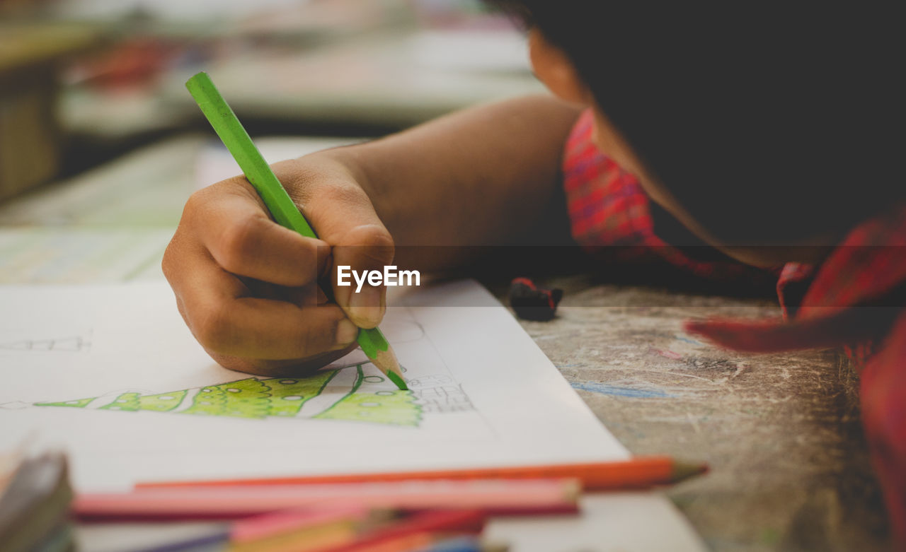 Boy drawing christmas tree on table at school