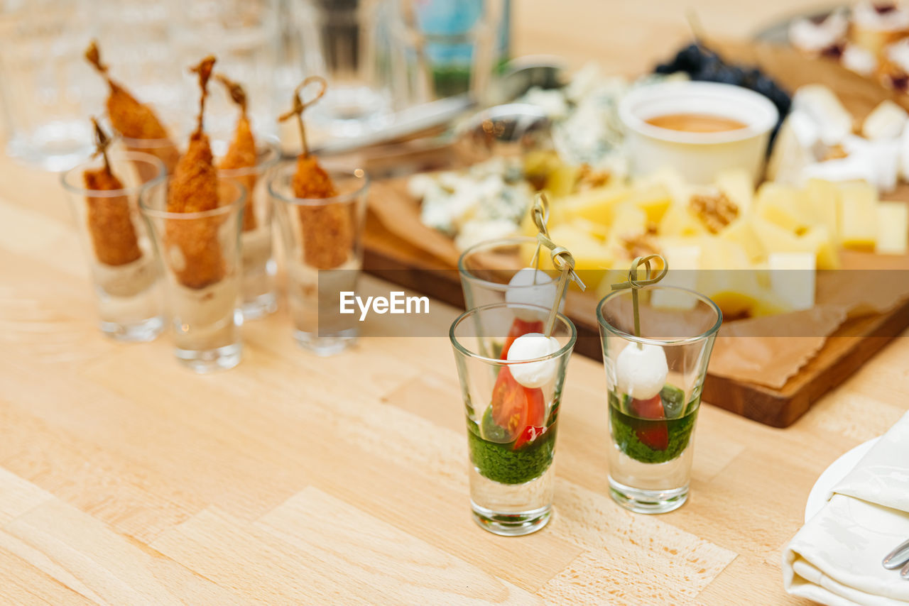 Catering, food and drinks concept - close up of different appetizers in glasses on table