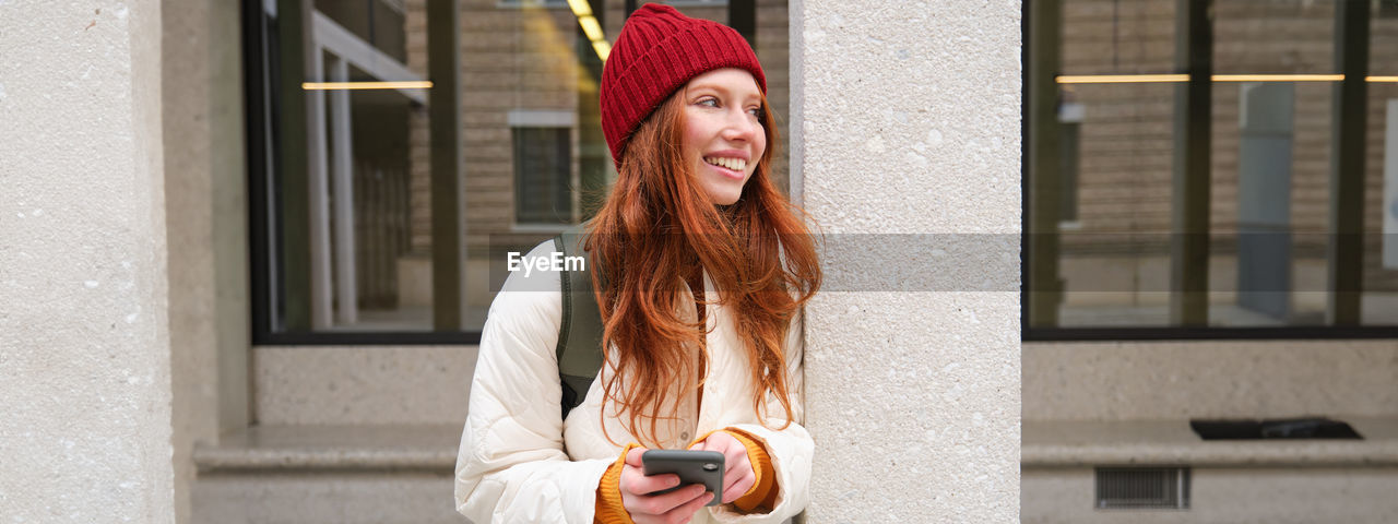 portrait of young woman using mobile phone in city