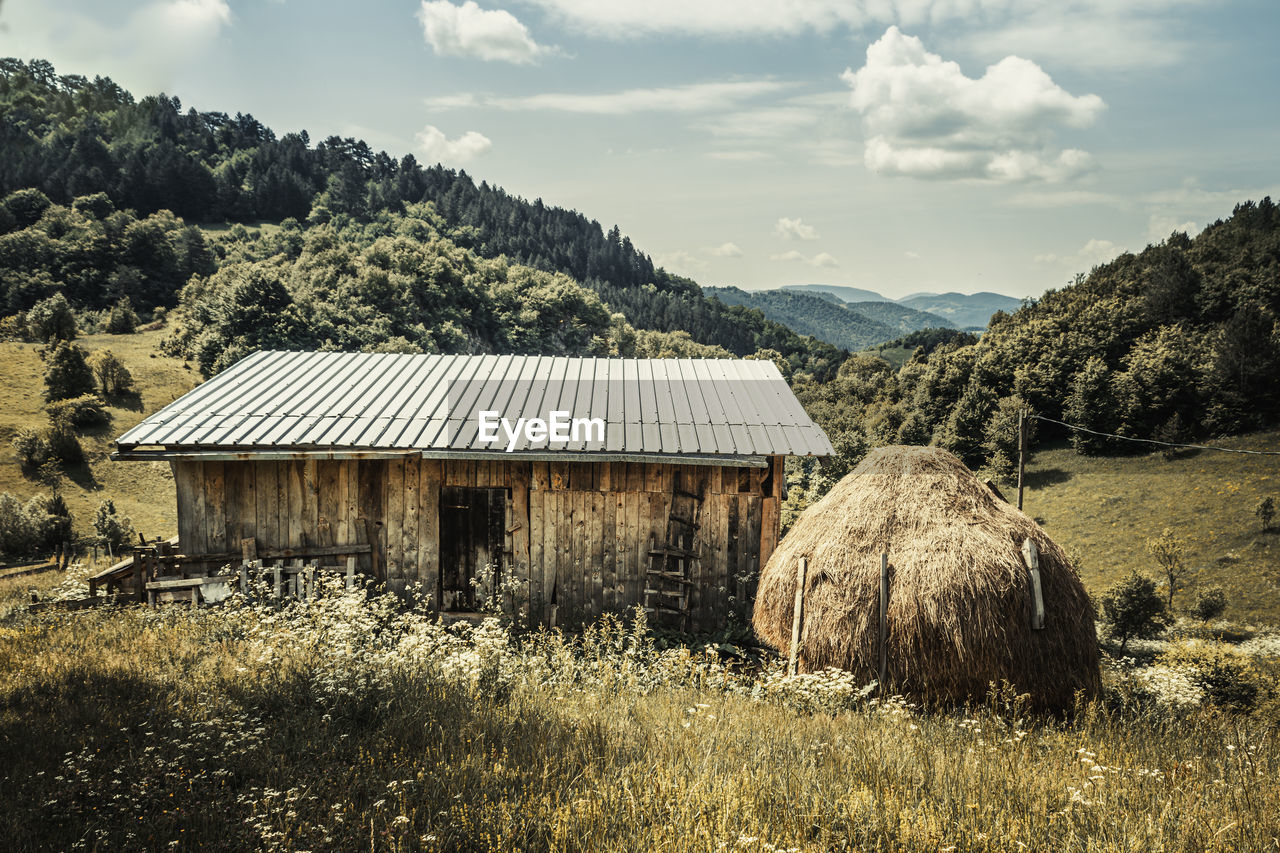 House on the field against the sky with a haystack