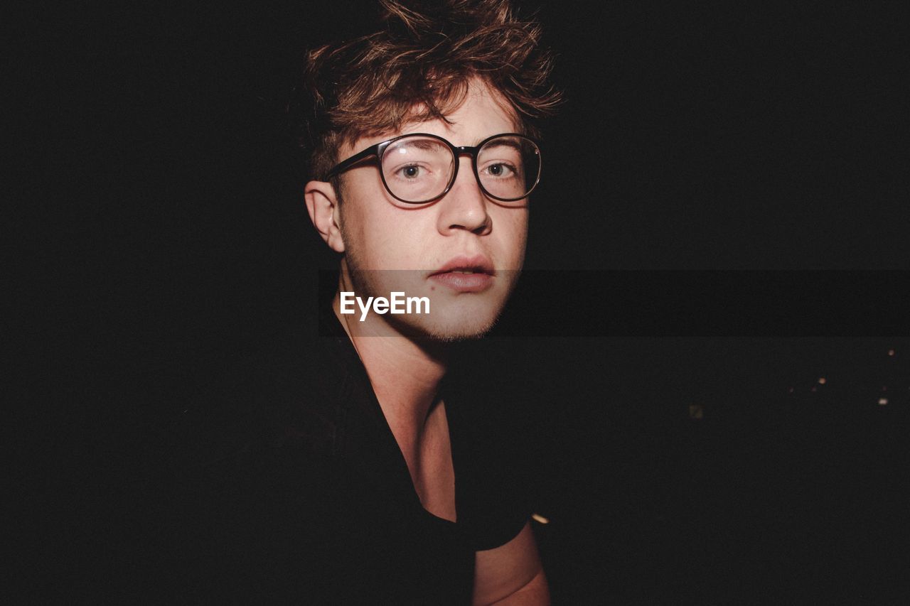 Portrait of young man wearing eyeglasses at night
