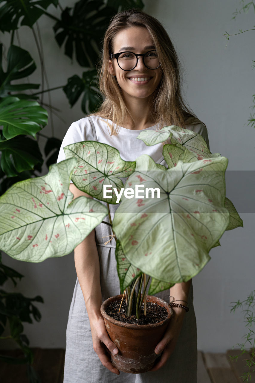 Portrait of smiling woman standing with potted plant