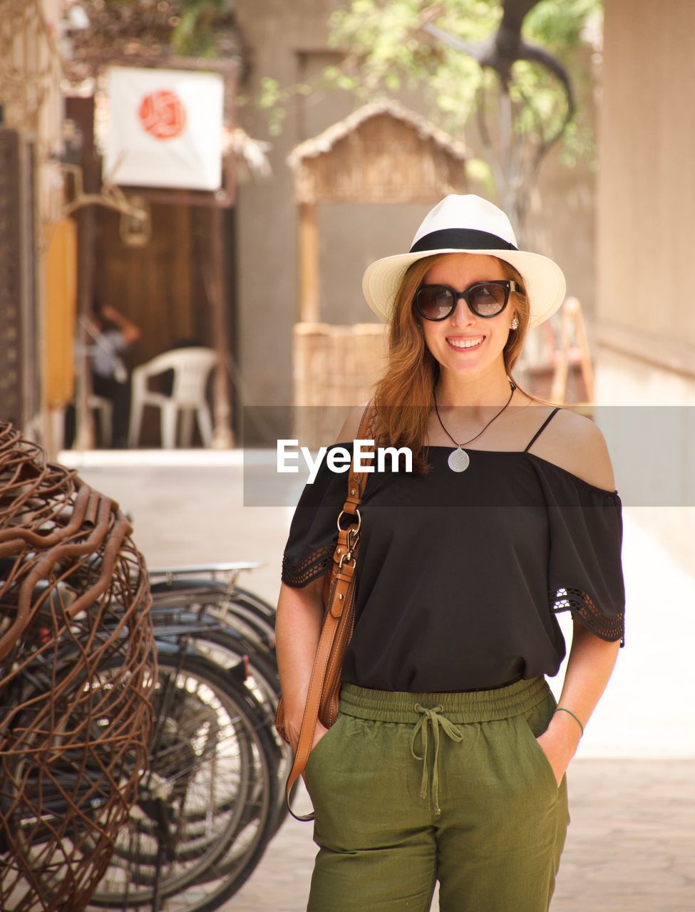 Smiling young woman wearing sunglasses standing on street