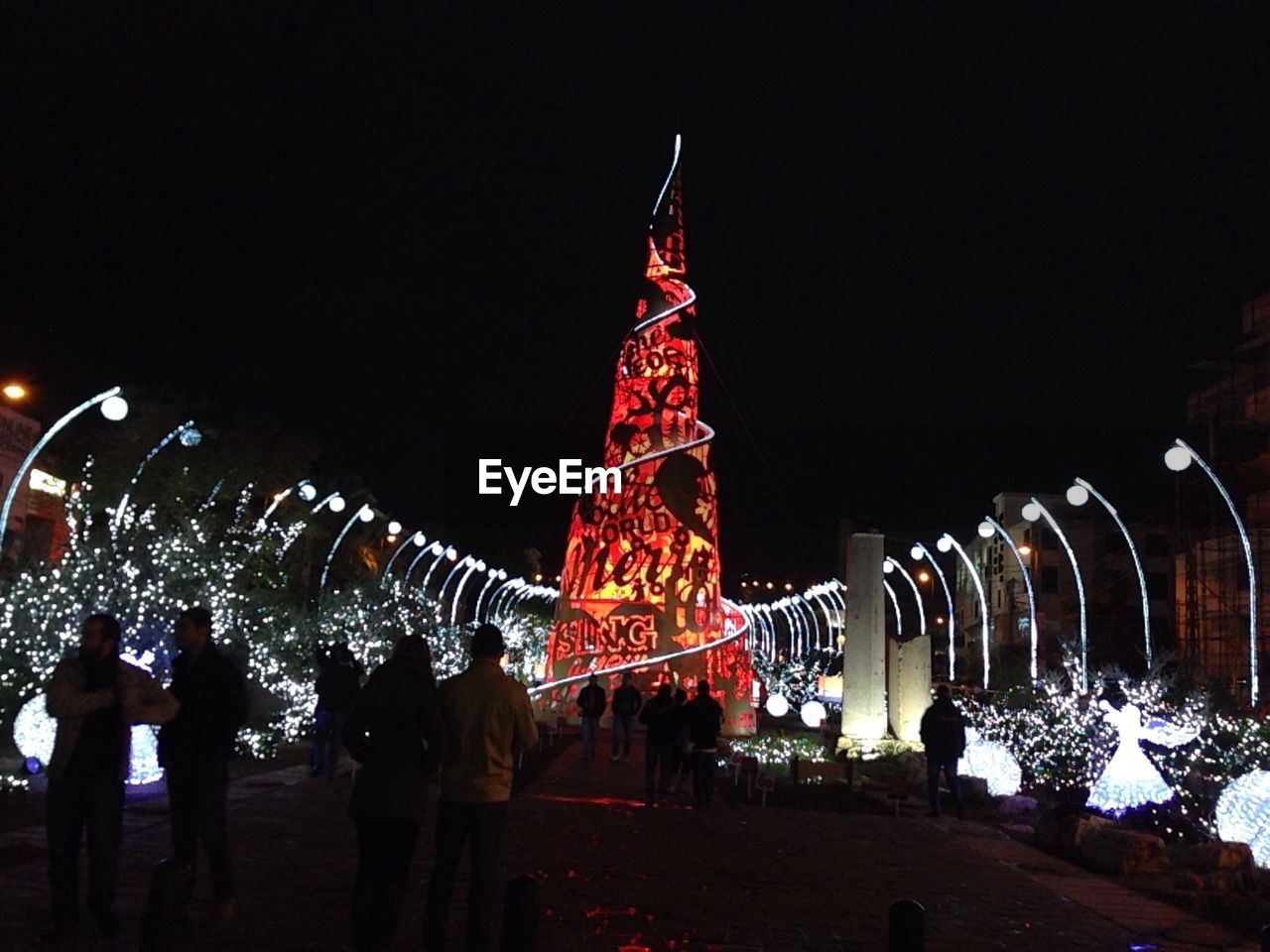 People looking at illuminated christmas decorations at night