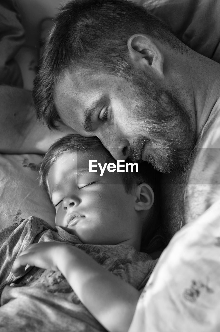 High angle view of father and son resting on bed