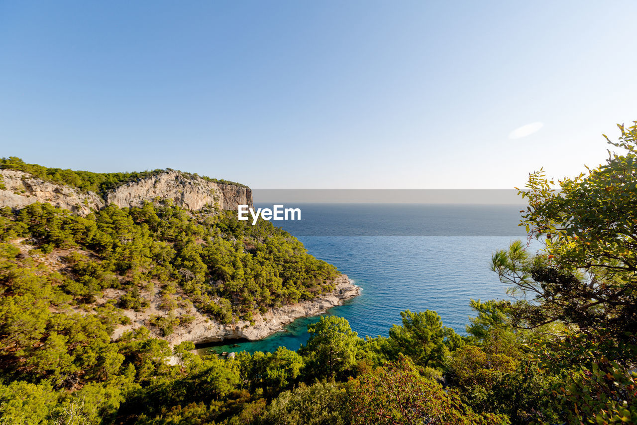 Big rock with forest and azure sea in summer