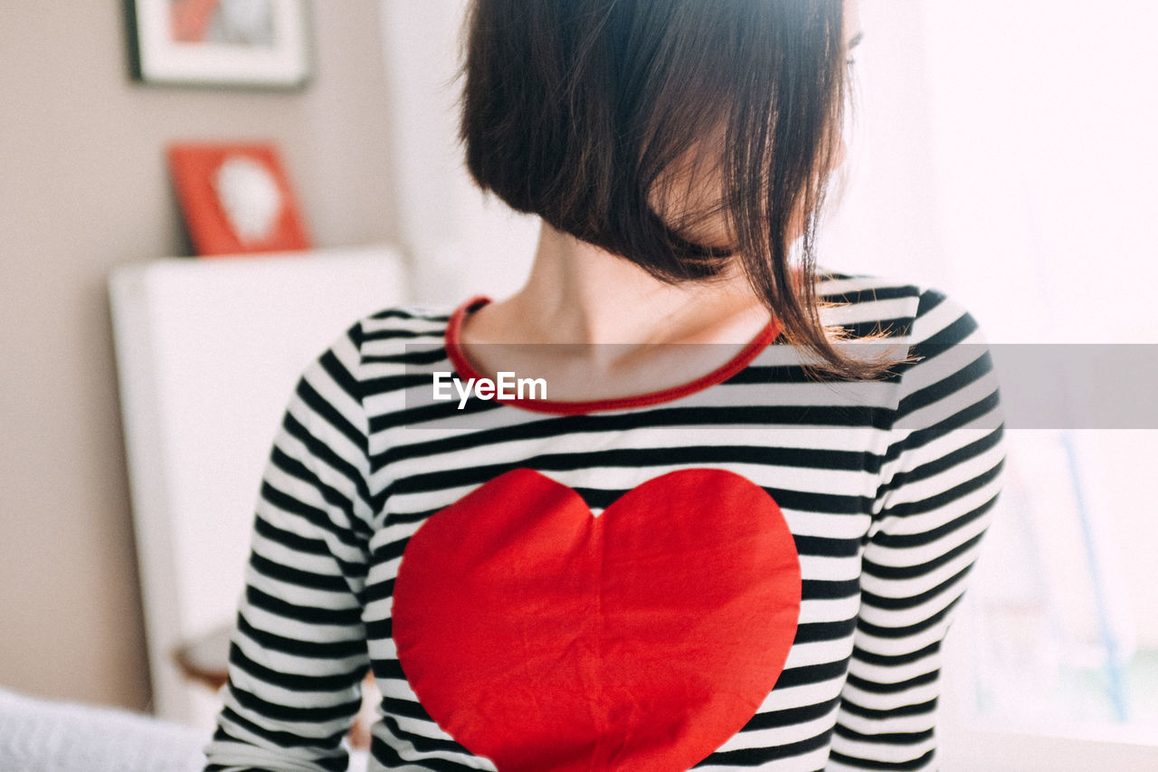 Woman with heart shape on t-shirt at home