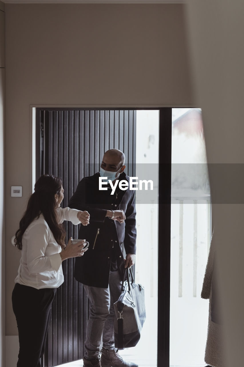 Male and female colleagues doing elbow bump while maintaining social distancing at home