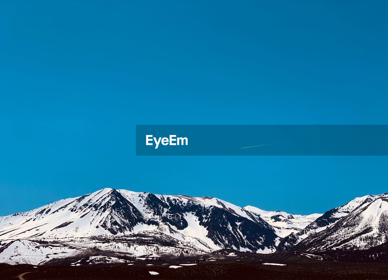 Scenic view of snowcapped mountains against clear blue sky