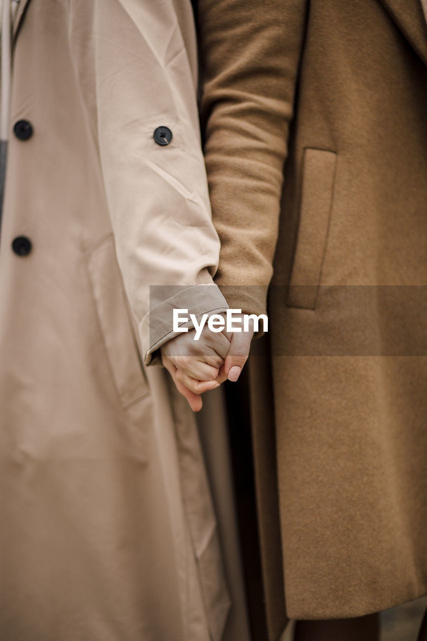 Women wearing overcoats holding hands