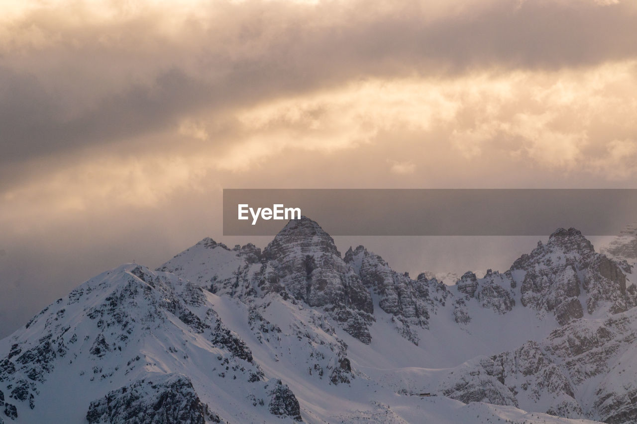 SNOWCAPPED MOUNTAINS AGAINST SKY DURING SUNSET